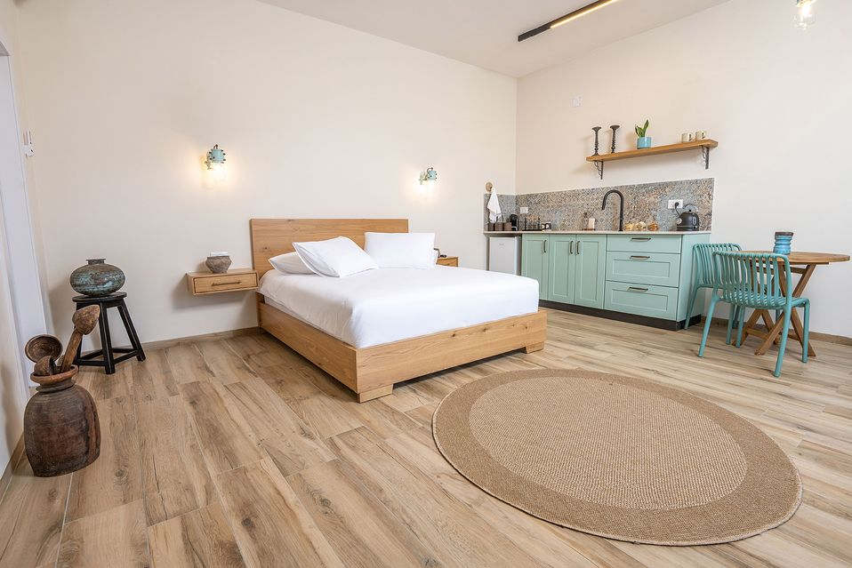 Suite interior with a wood bed, a mint-green kitchenette, and a round jute rug