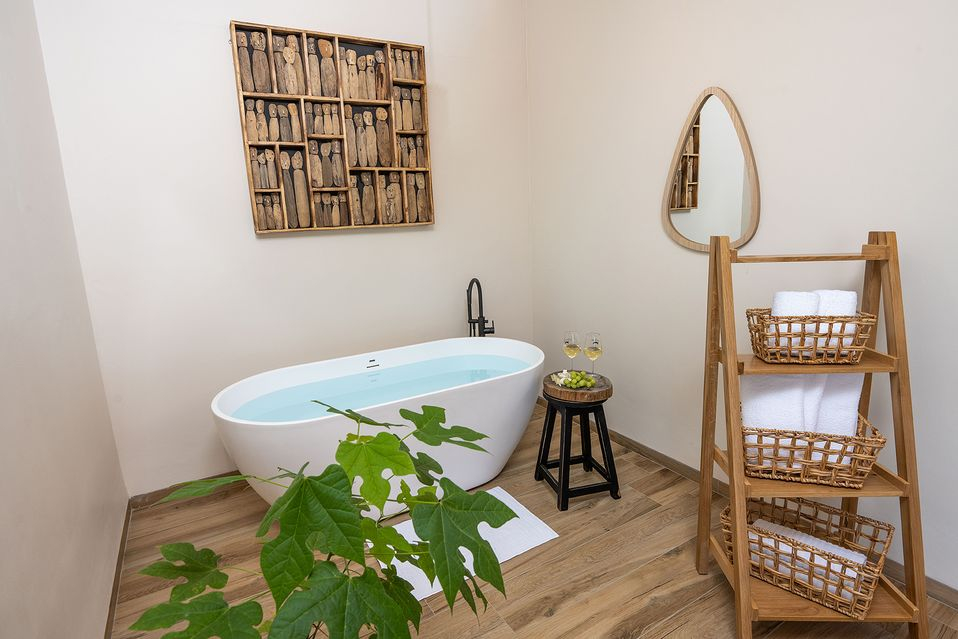 Bathroom detail with a freestanding tub, a wood ladder shelf with towels, wall art, and a plant