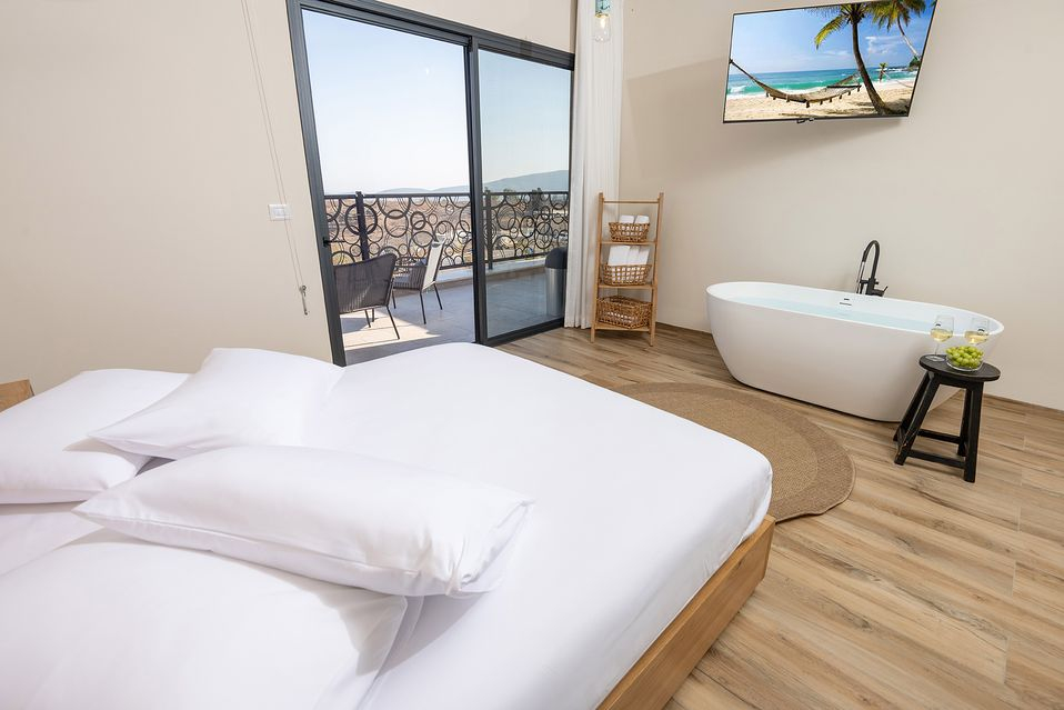 Suite interior with the bed, a freestanding bathtub, and a sliding door to the terrace