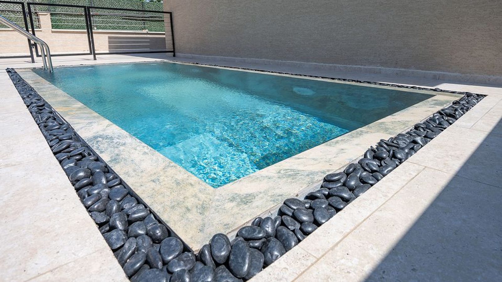 Heated private pool with a stone surround and patio in daylight