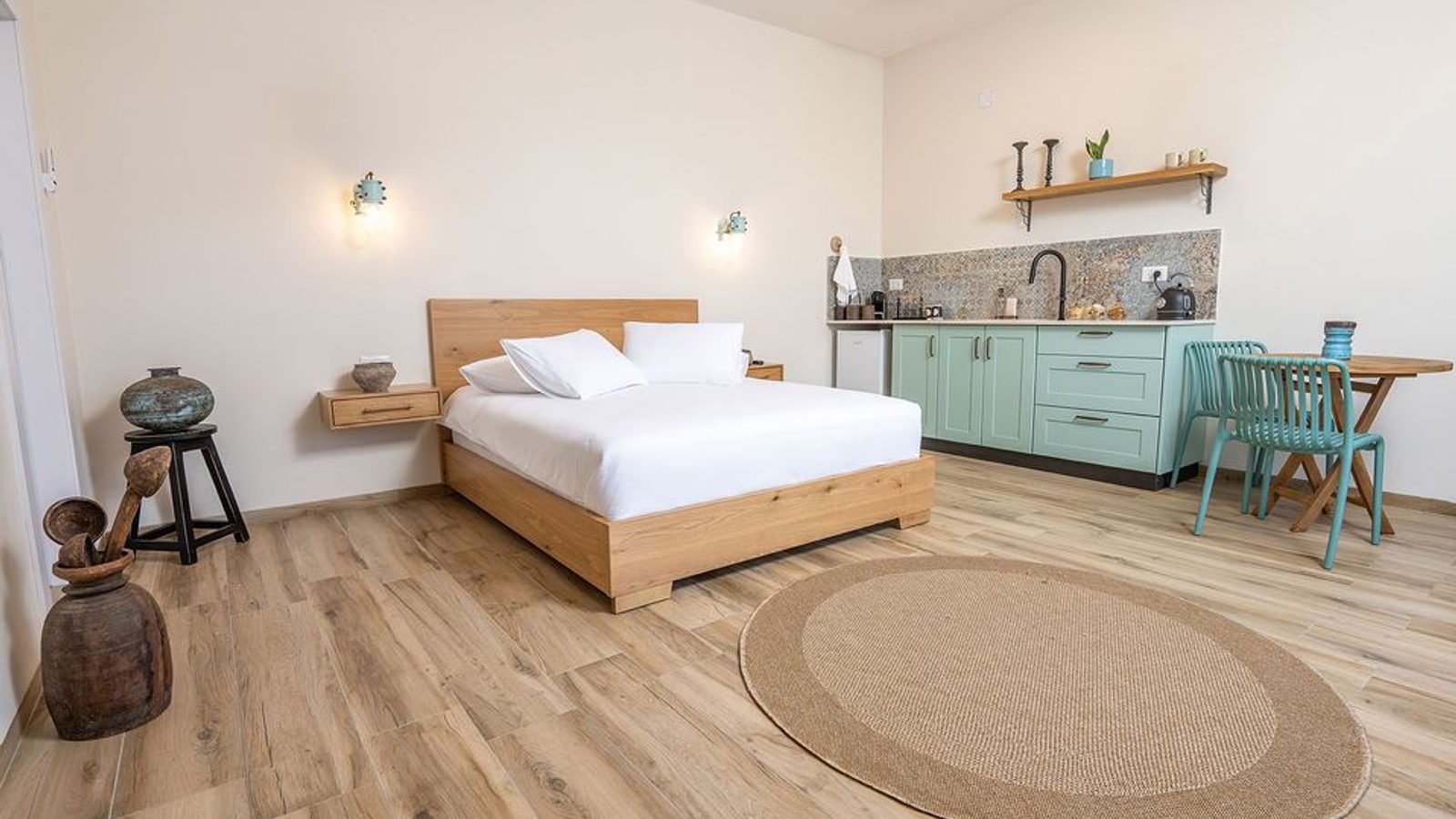 Suite interior with a wood bed, a mint-green kitchenette, and a round jute rug